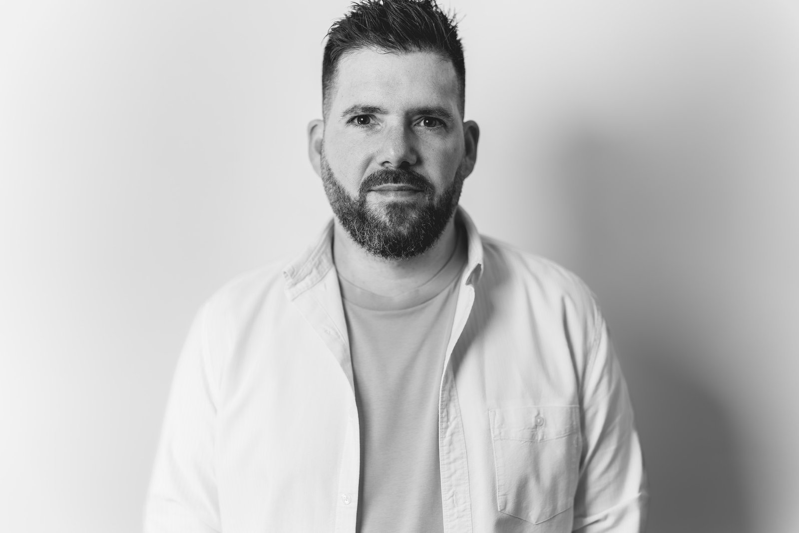 Portrait noir et blanc de Cyril Steau, photographe à Paris, en chemise blanche sur fond clair
